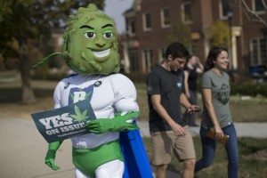 Buddie, the mascot for the pro-marijuana legalization group ResponsibleOhio, waits on a sidewalk to greet passing college students during a promotional tour bus at Miami University, Friday, Oct. 23, 2015, in Oxford, Ohio. A ballot proposal before Ohio voters this fall would be the first in the Midwest to take marijuana use and sales from illegal to legal for both personal and medical use in a single vote. (AP Photo/John Minchillo)